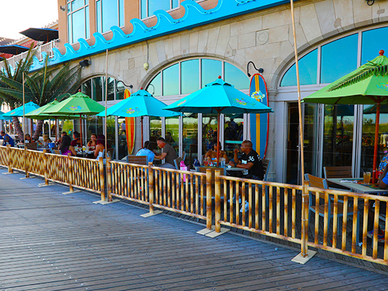 Tables and chairs under large umbrellas along the wall